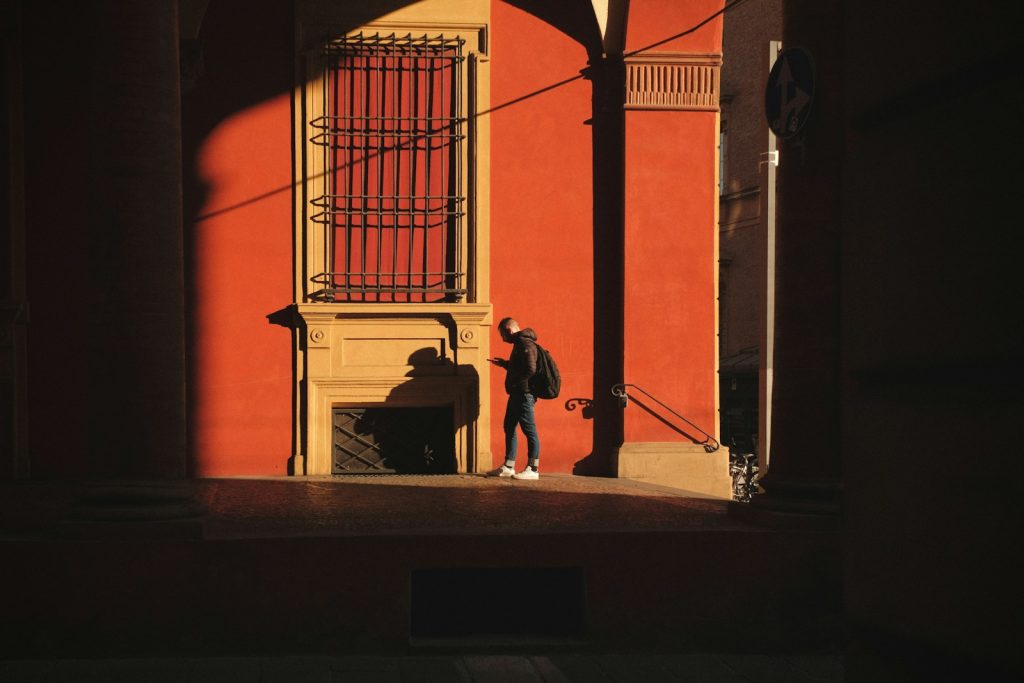 Person standing against a red wall with strong shadows